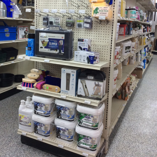 Store aisle displaying various grooming tools and supplies. Items include brushes, clippers, and buckets, evoking a practical and organized tone.