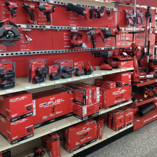 Store display of Milwaukee tools. Red and black power tools with packaging on shelves. Branding and 